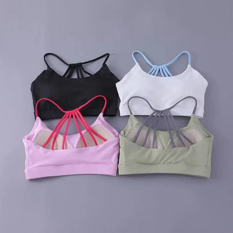 Four sports bras in black, white, pink, and green on a gray background