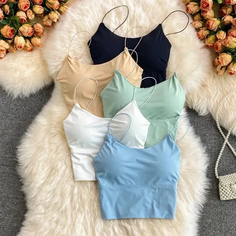 Four crop tops in different colors on a fluffy white surface with flowers in the background.
