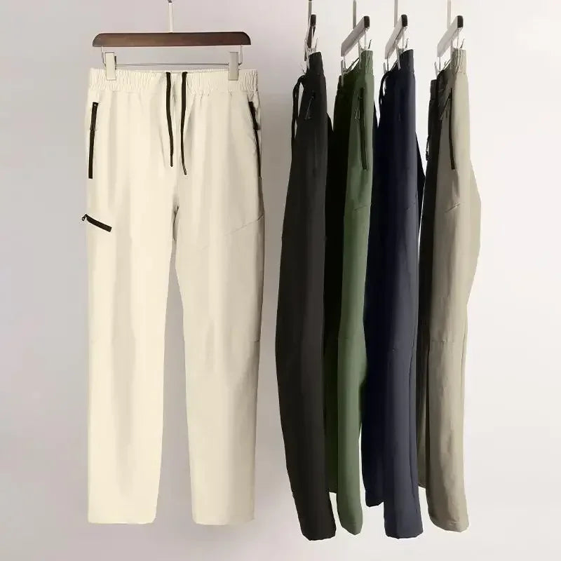 Set of pants in various colors hanging on a rack against a plain background