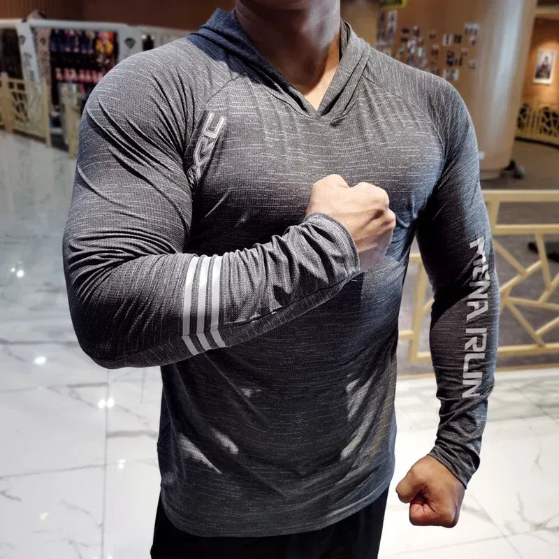 Person wearing a gray athletic hoodie with branding, flexing muscles in an indoor setting.