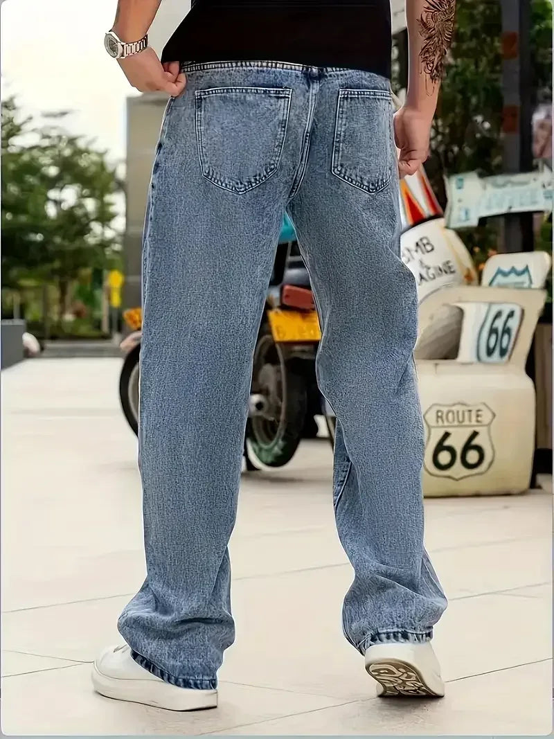Person wearing blue jeans standing on a sidewalk with a blurred background