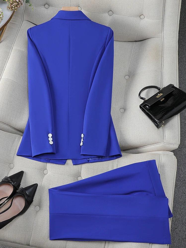 Blue suit jacket and pants on a gray sofa with black shoes and handbag.