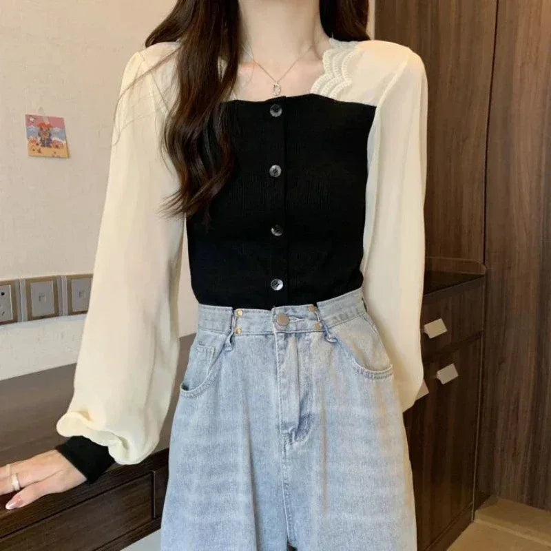 Person wearing a black button-up top, cream cardigan, and light blue jeans indoors.