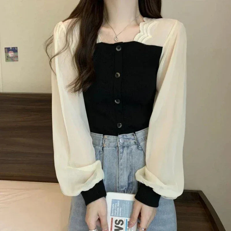 Person wearing a black top, beige cardigan, and blue jeans holding a newspaper.