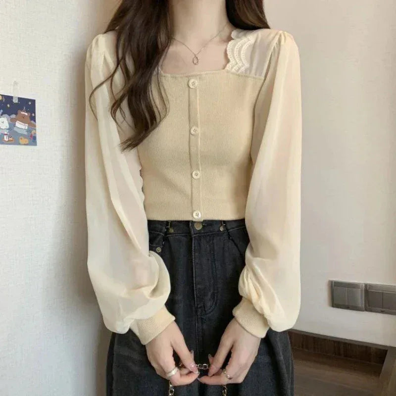 Person wearing a beige blouse with puffed sleeves and a black skirt indoors.