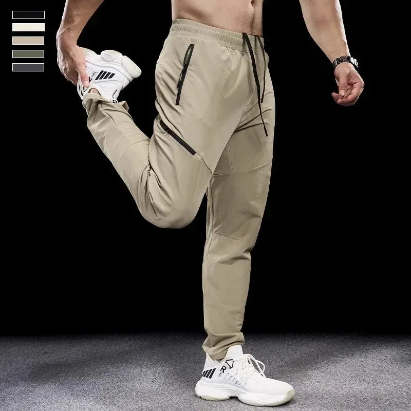 Person wearing beige athletic pants and white sneakers on a black background
