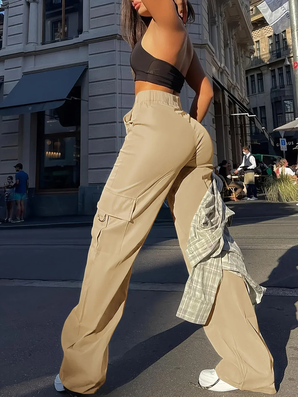 Person wearing a black sports bra and beige cargo pants on a city street.