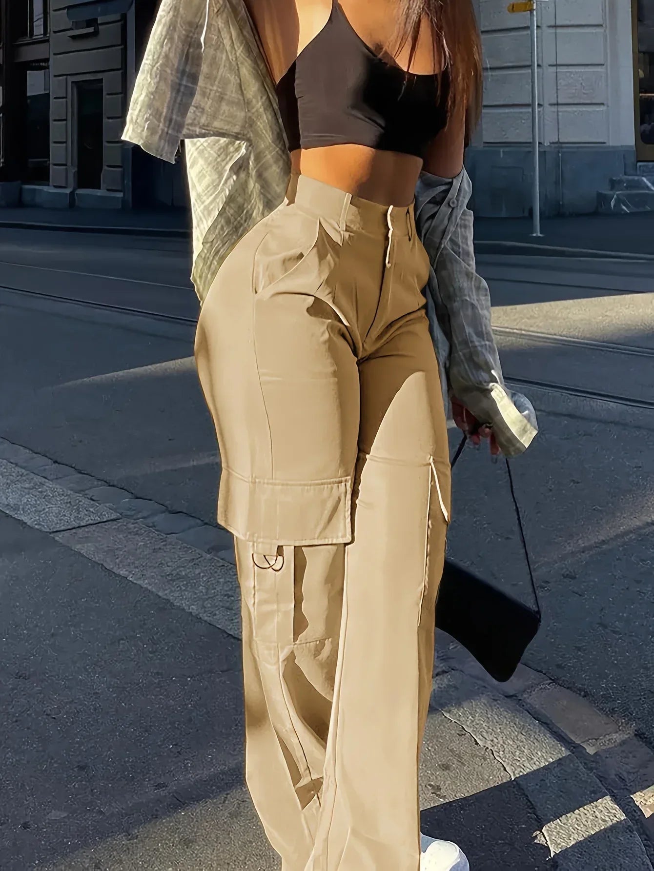 Person wearing beige cargo pants and a black sports bra on a city street.