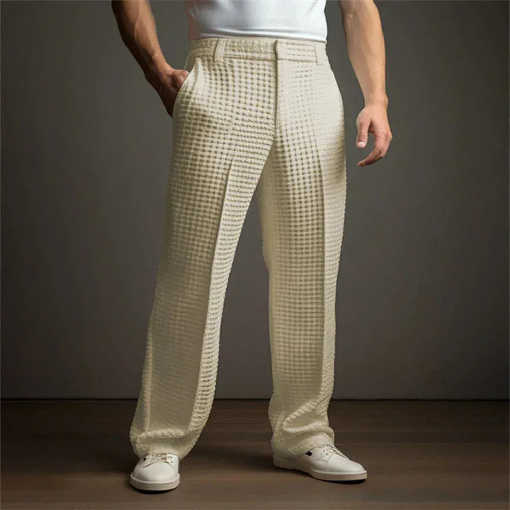 Person wearing beige checkered pants and white shoes on a dark background