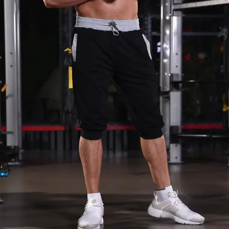 Person wearing black athletic shorts and white sneakers in a gym setting