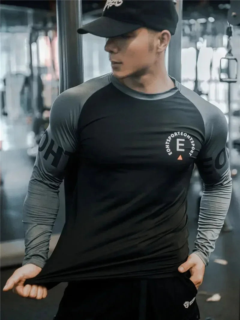 Person wearing a black and gray athletic shirt with branding in an indoor setting