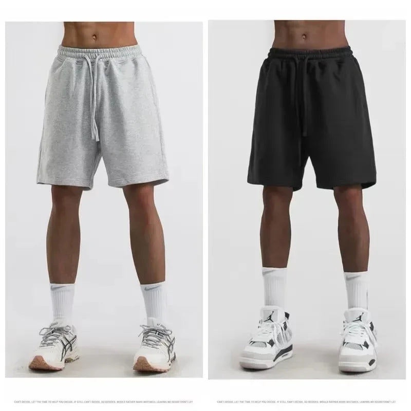 Two pairs of shorts, one gray and one black, worn by a person on a white background.