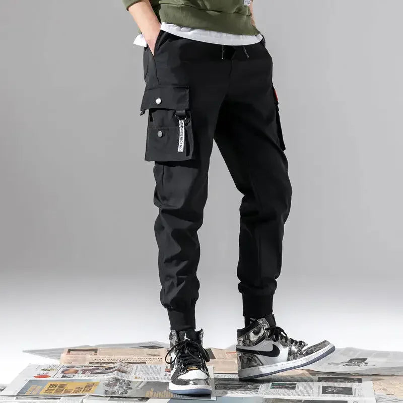 Person wearing black cargo pants with a gray background