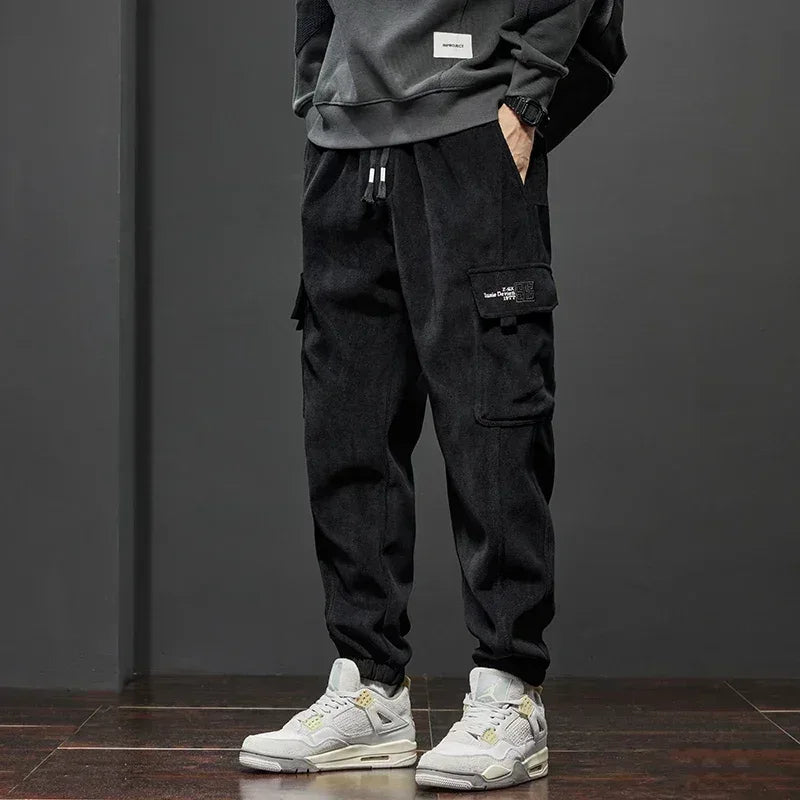 Person wearing black cargo pants and white sneakers against a dark background