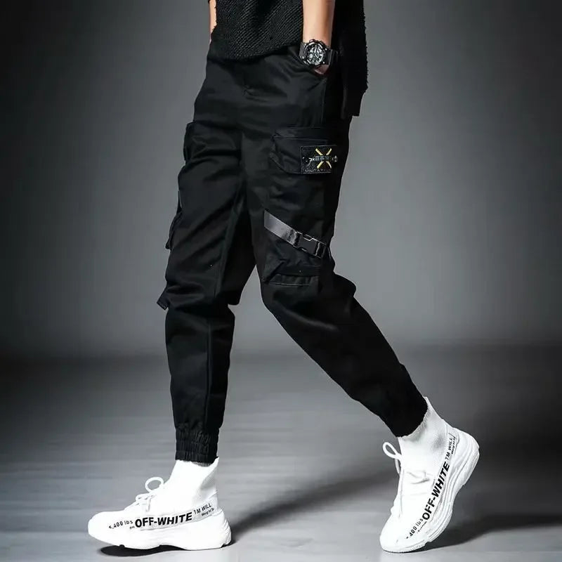 Person wearing black cargo pants and white sneakers on a gray background