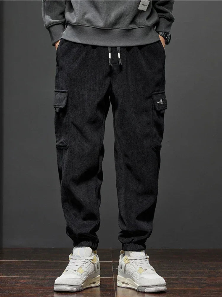 Person wearing black cargo pants and white sneakers on a dark background