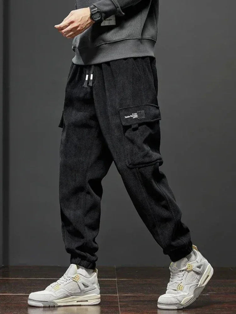 Person wearing black cargo pants and white sneakers on a dark background