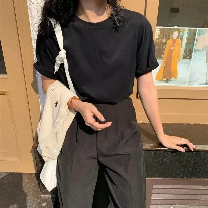 Person wearing a black outfit with a beige wall and window in the background