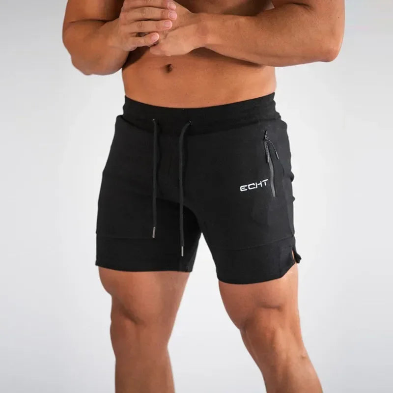 Person wearing black shorts with a brand logo on a plain background