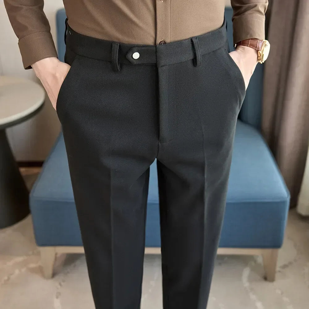 Person wearing a brown shirt and black pants standing in a room with a blue chair and gray floor.