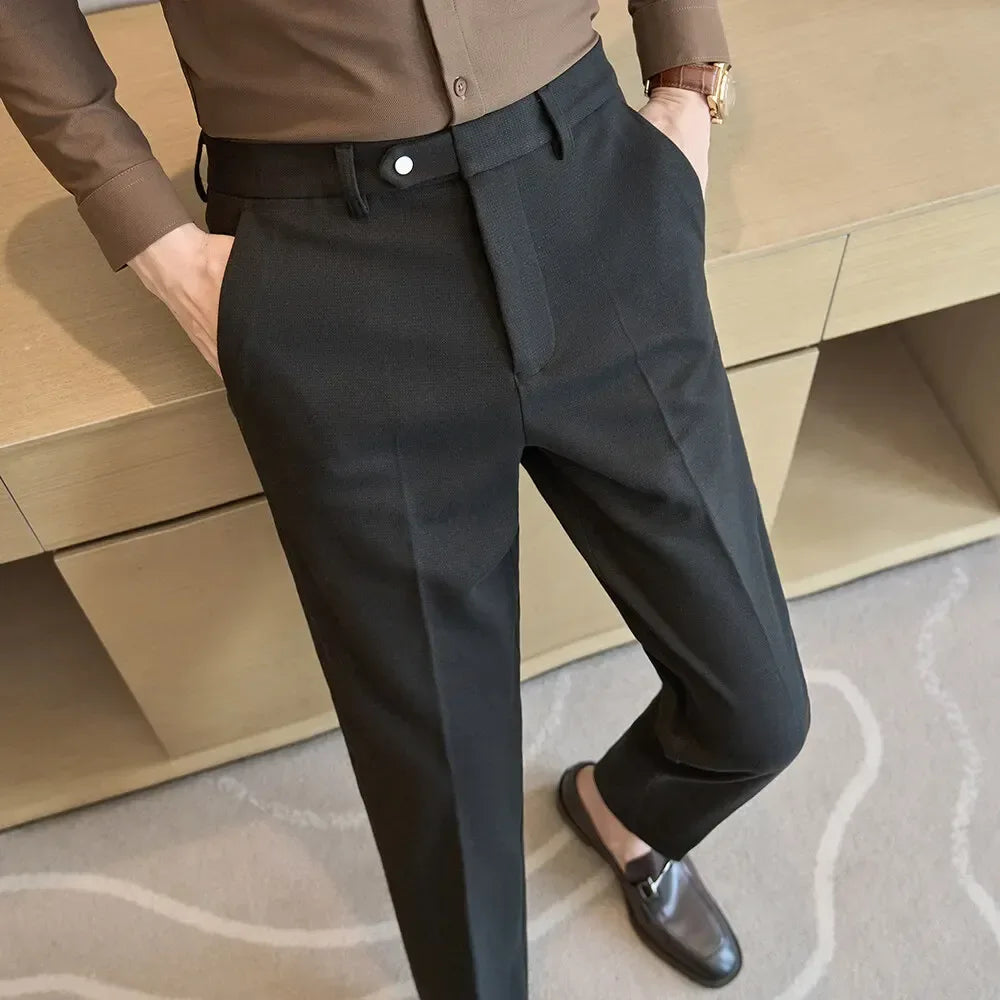 Person wearing dark gray pants with a brown shirt and shoes in front of beige furniture.