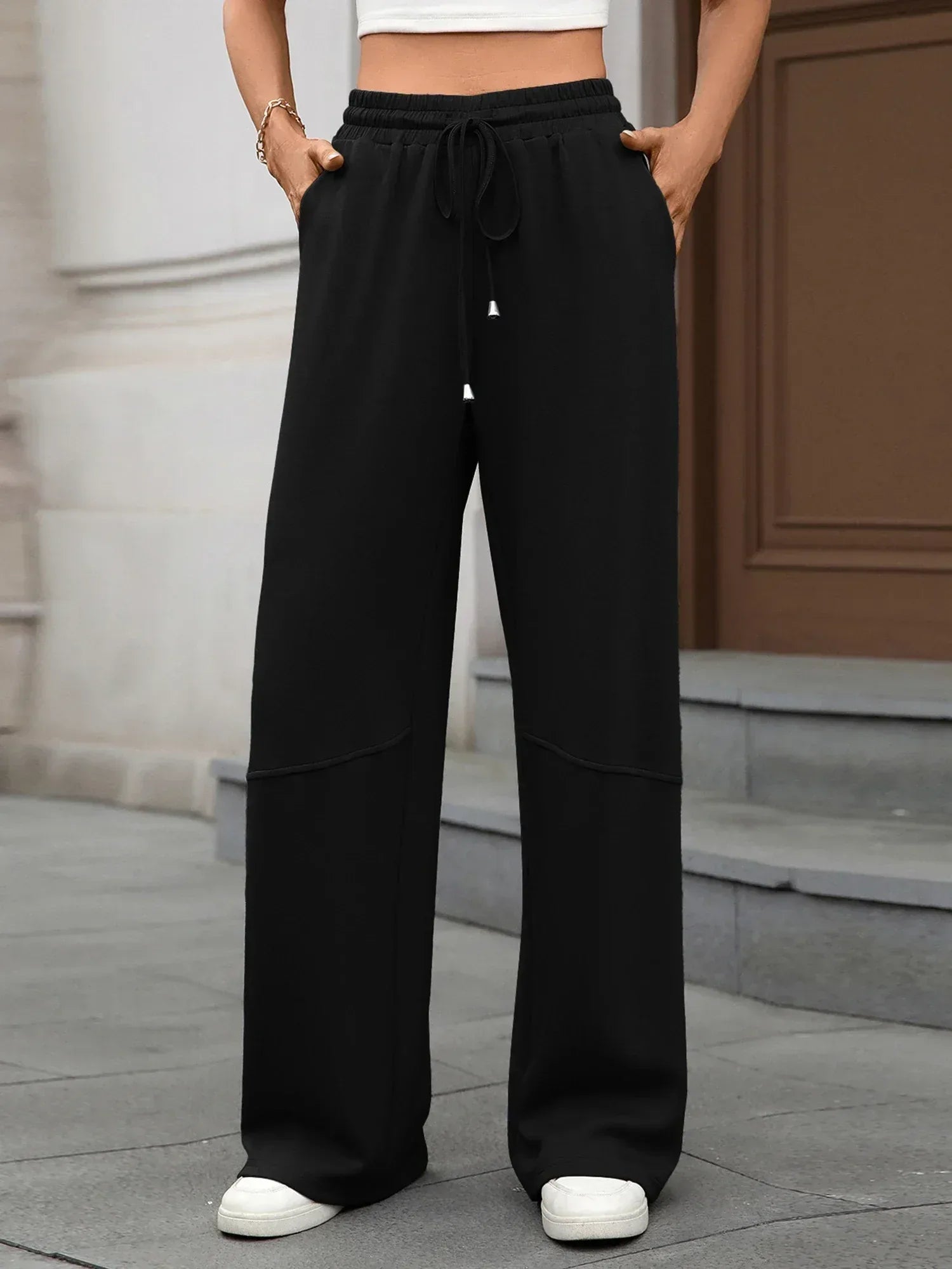 Person wearing black wide-leg pants with a neutral background