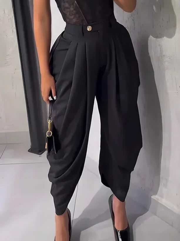 Person wearing black high-waisted pants with a plain background
