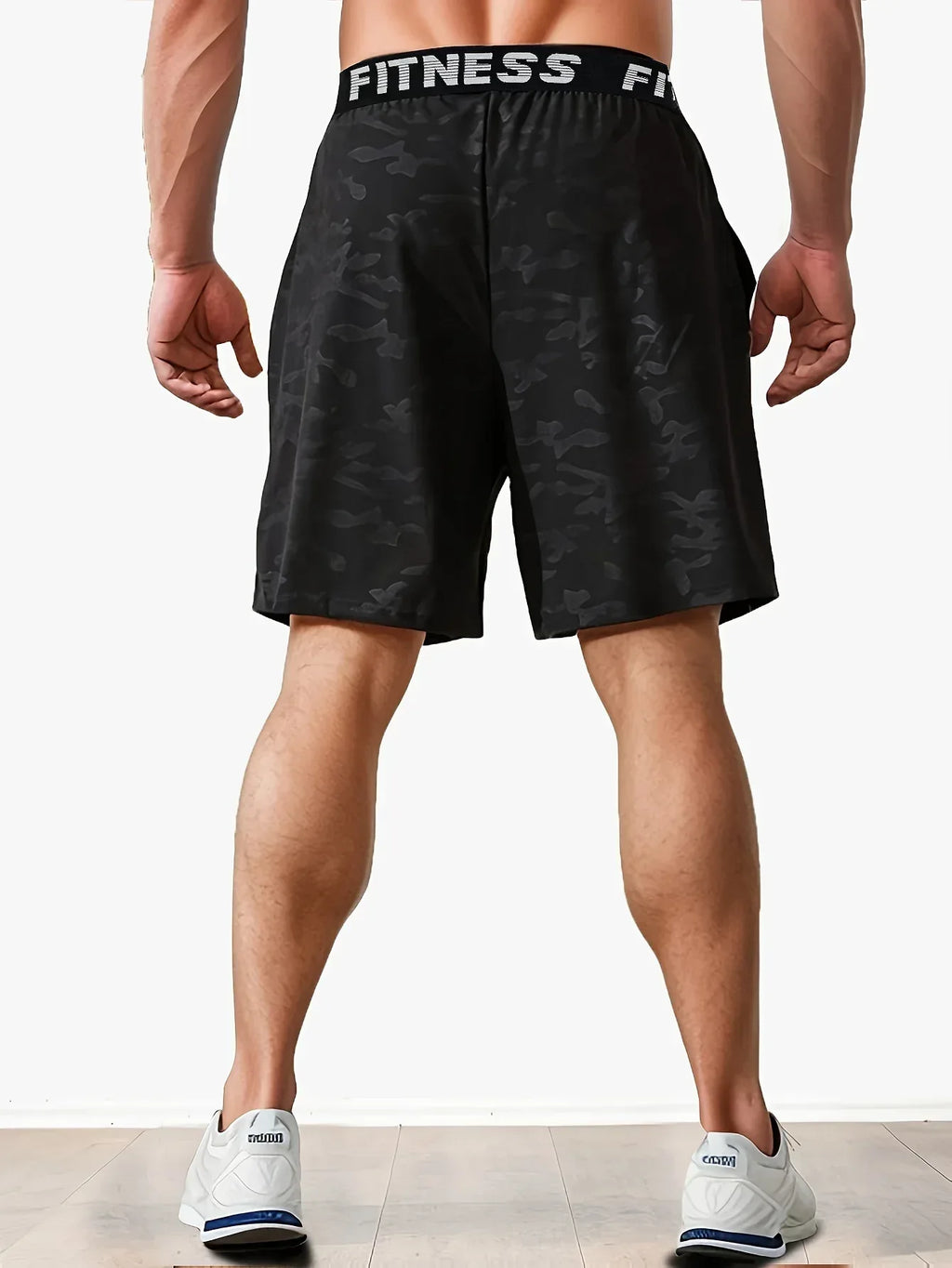 Person wearing black camouflage shorts with 'Fitness' waistband on a white background