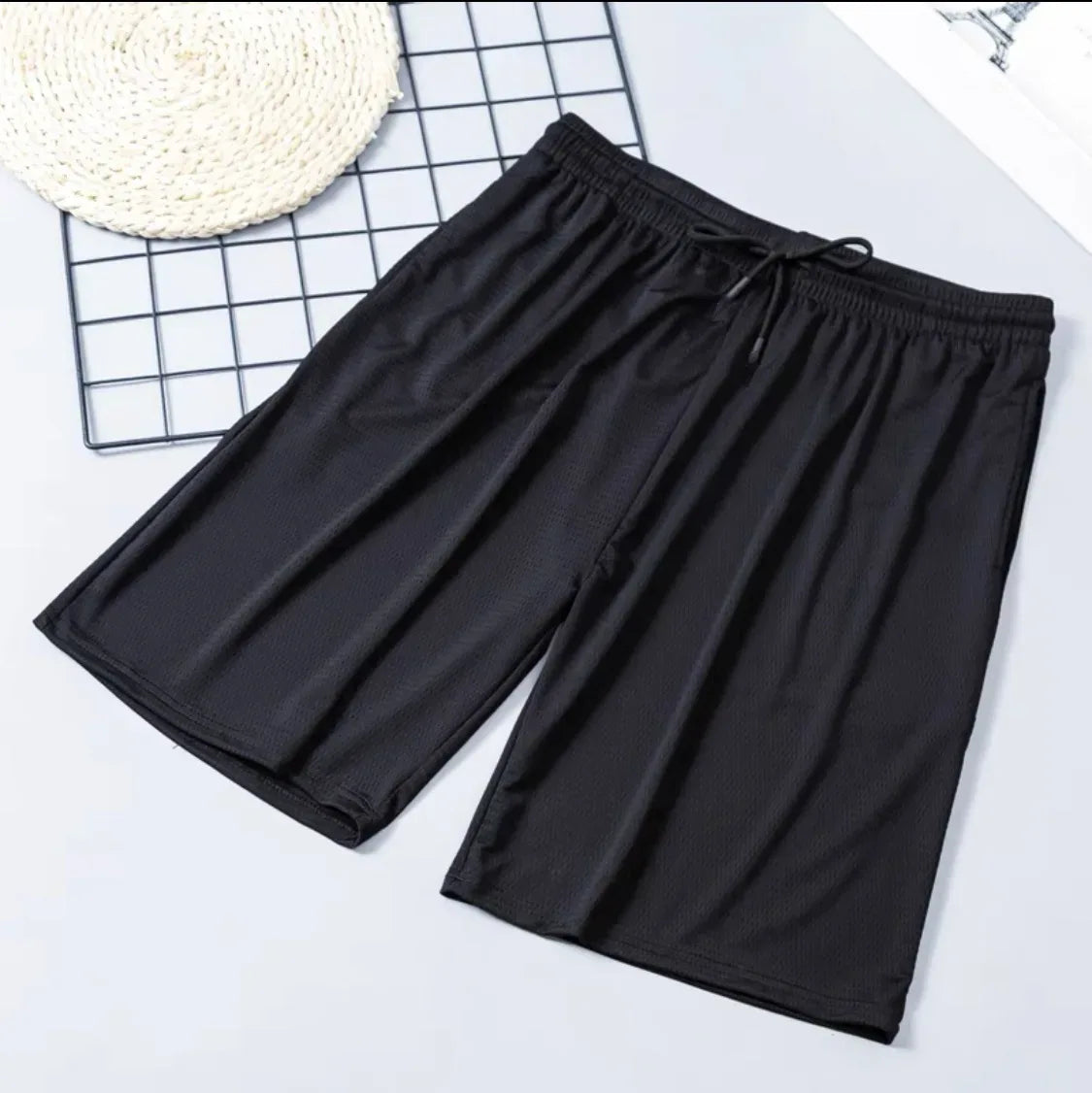 Black shorts on a white surface with a grid pattern in the background