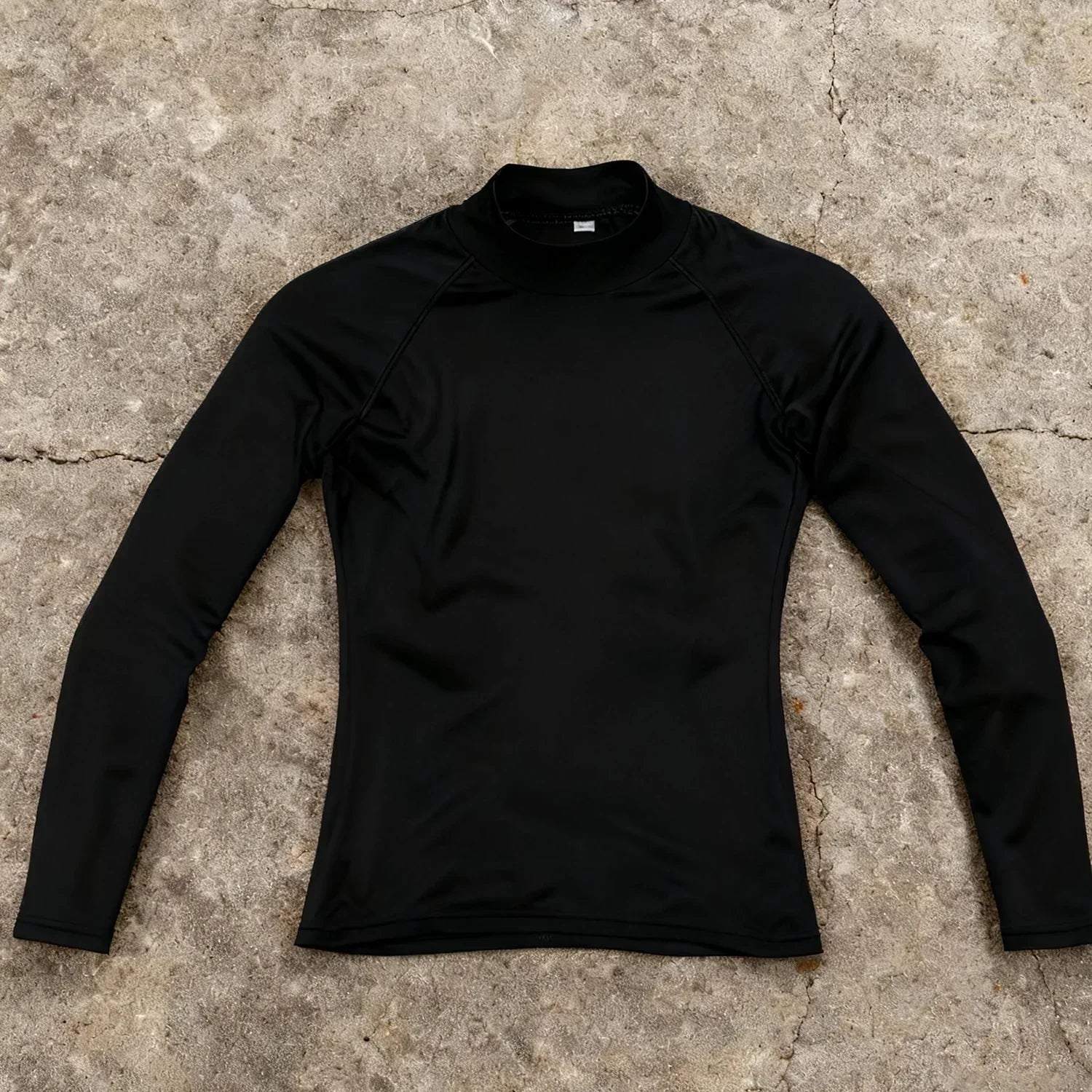 Black long-sleeve shirt on a textured concrete surface