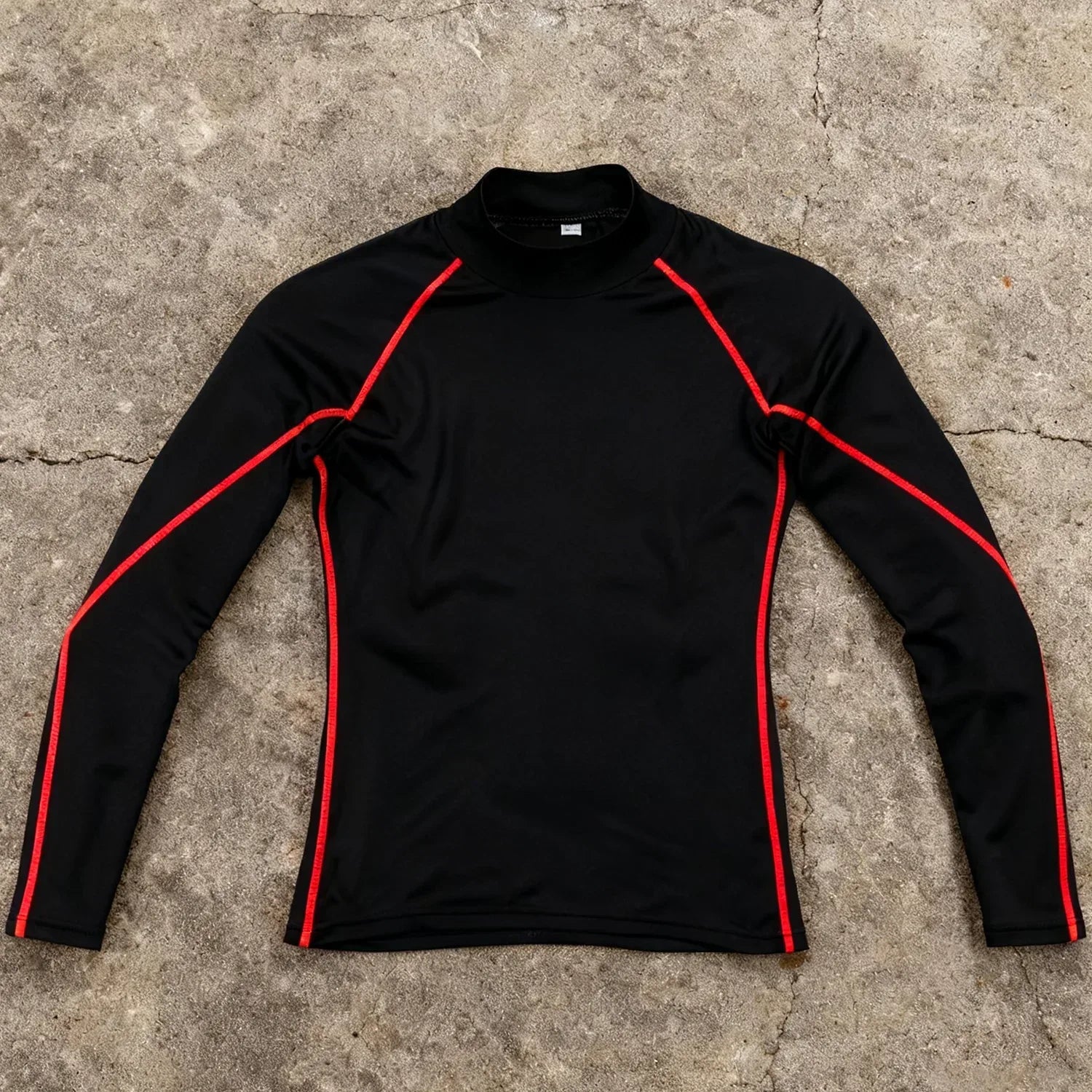 Black long-sleeve shirt with red accents on a concrete surface