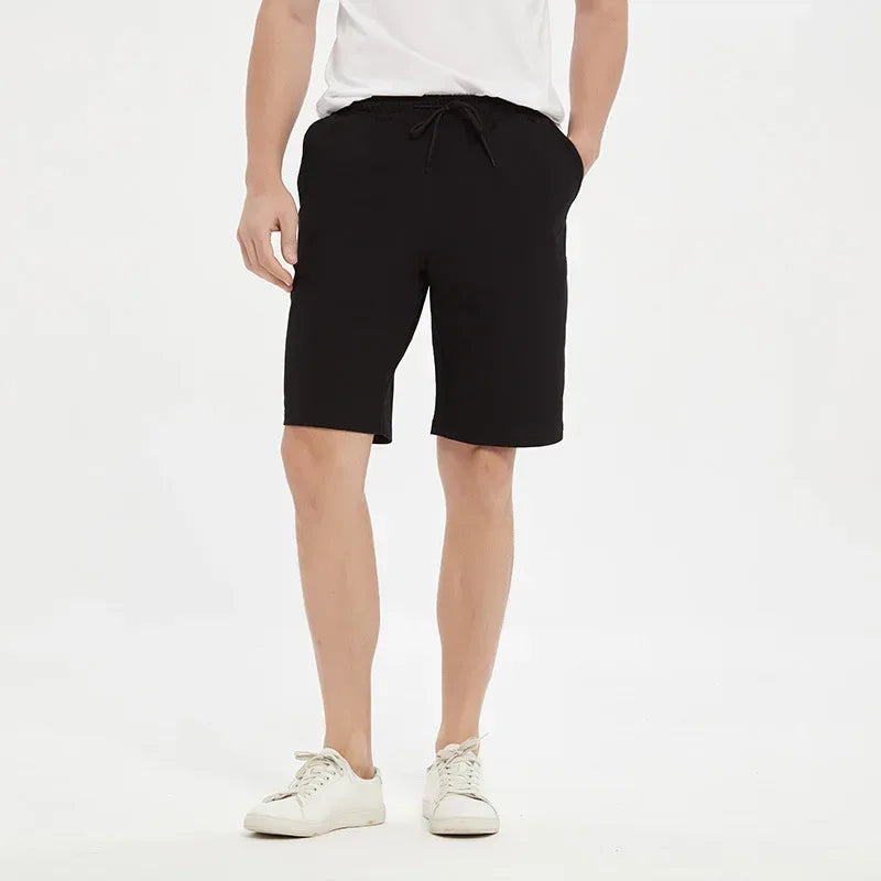 Person wearing black shorts and white sneakers on a white background