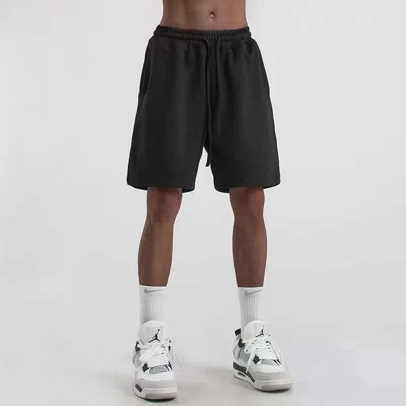 Person wearing black shorts and white sneakers on a plain background