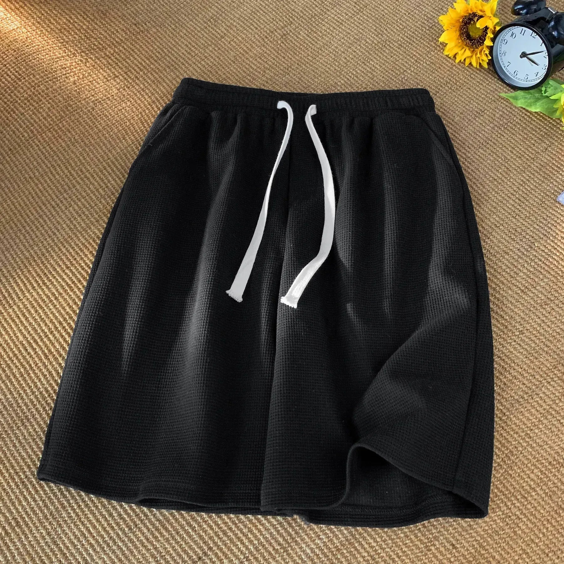 Black shorts with white drawstring on a textured brown surface