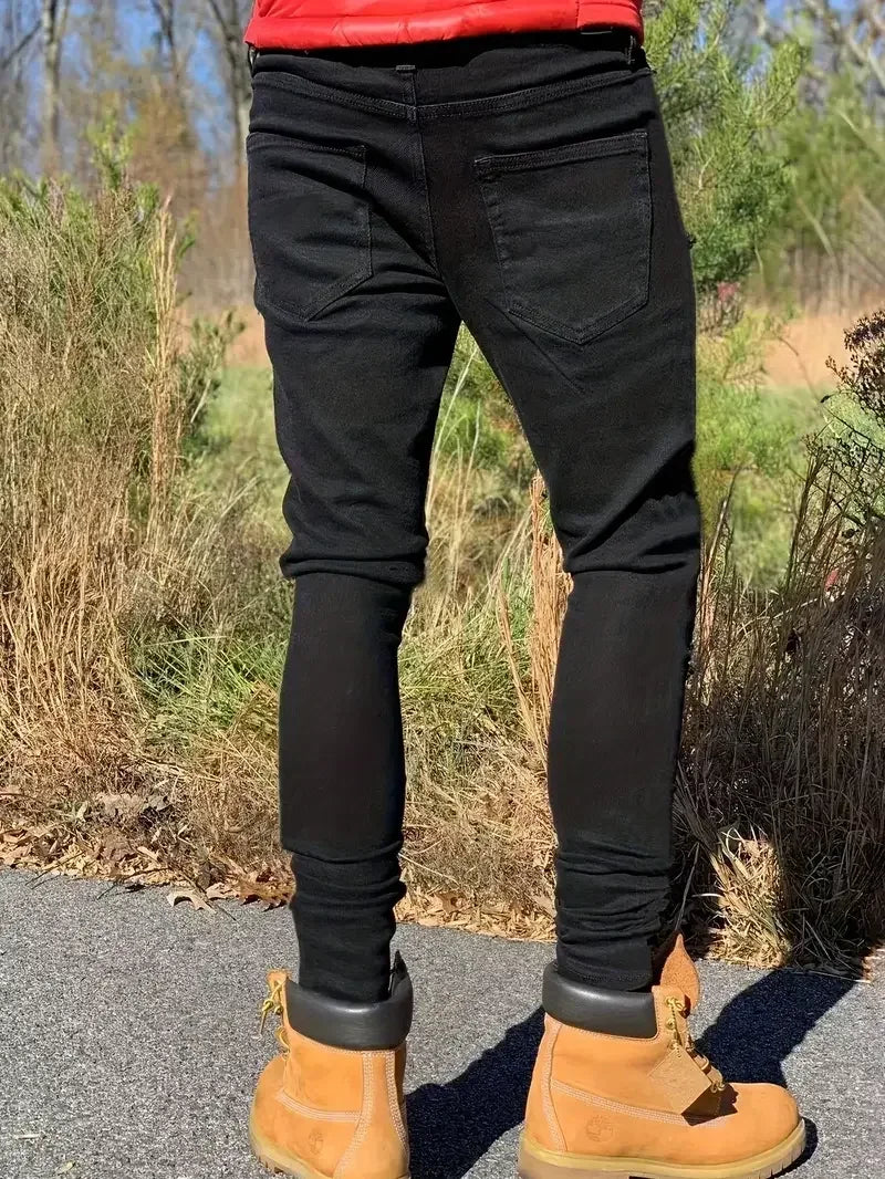 Person wearing black pants and tan boots standing outdoors with a natural background