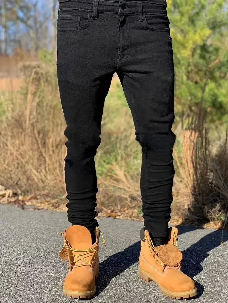 Person wearing black pants and tan boots standing on a road with a natural background