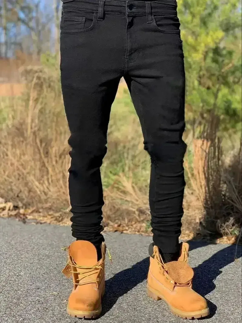 Person wearing black pants and tan boots standing on a road with a natural background