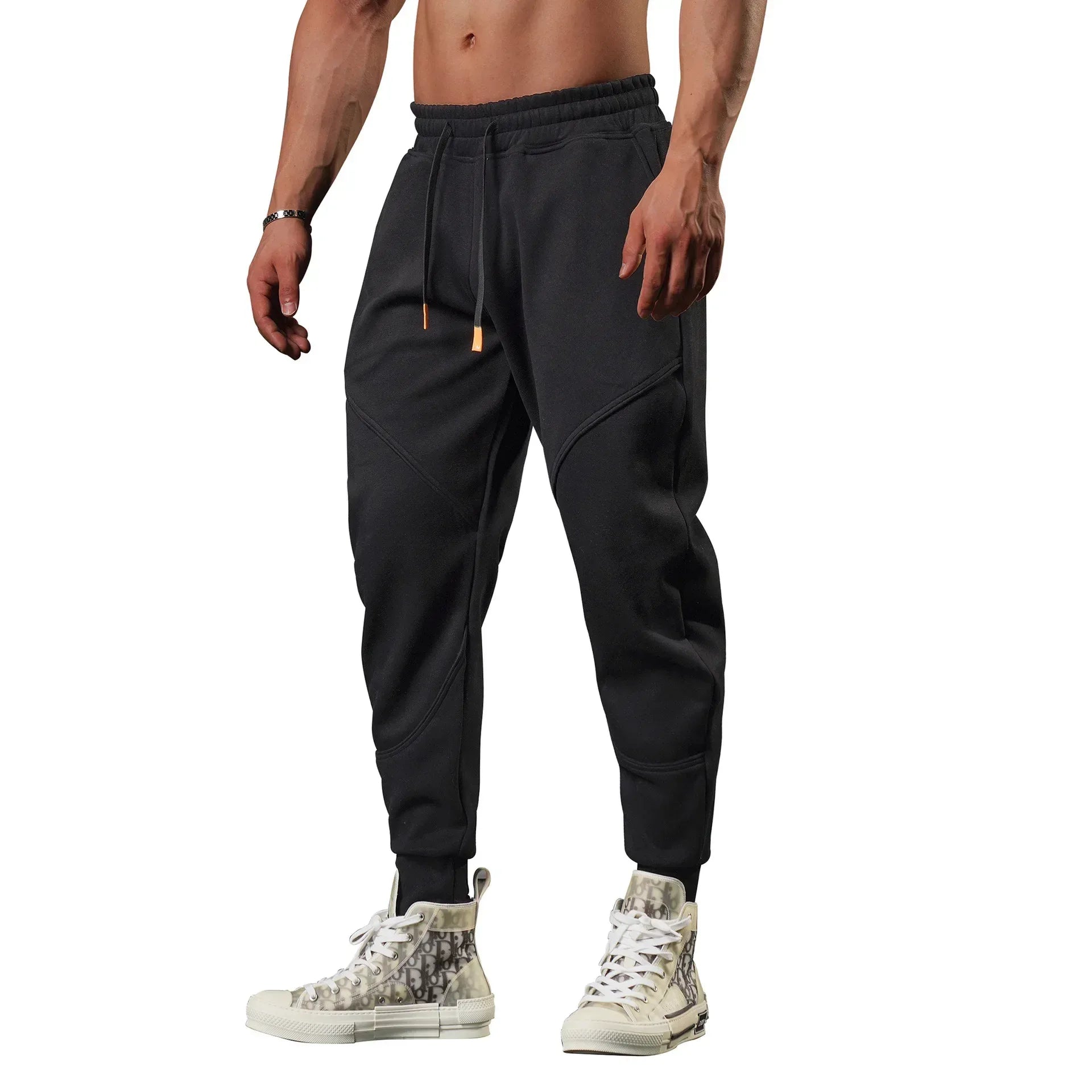 Person wearing black jogger pants with a white background