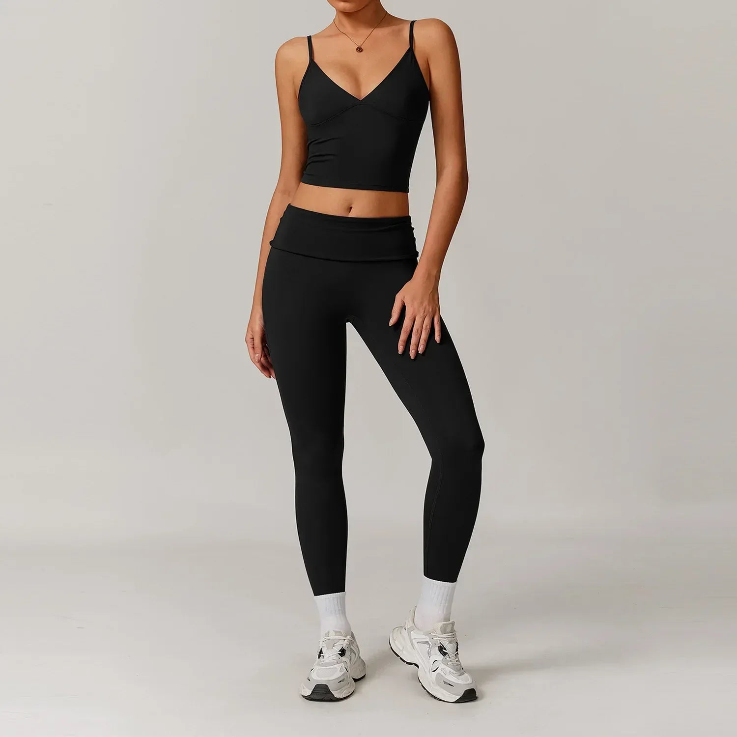 Woman wearing a black v-neck tank top and high waisted tight leggings with tummy control for a slimming seamless workout outfit - BetterPlace