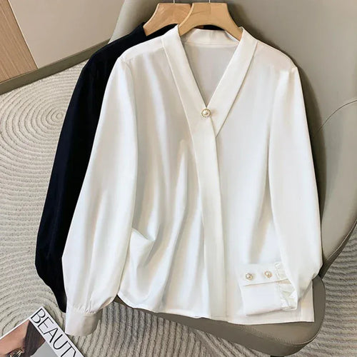 White blouse with long sleeves on a hanger against a neutral background