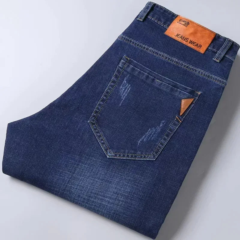 Folded blue jeans with a brand label on a light gray background