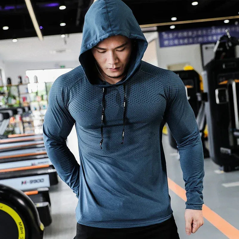 Man wearing a blue hoodie in a gym setting