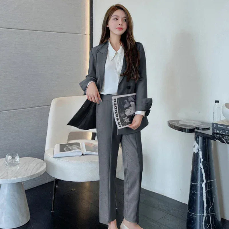 Woman in a gray suit holding a magazine in a modern interior setting