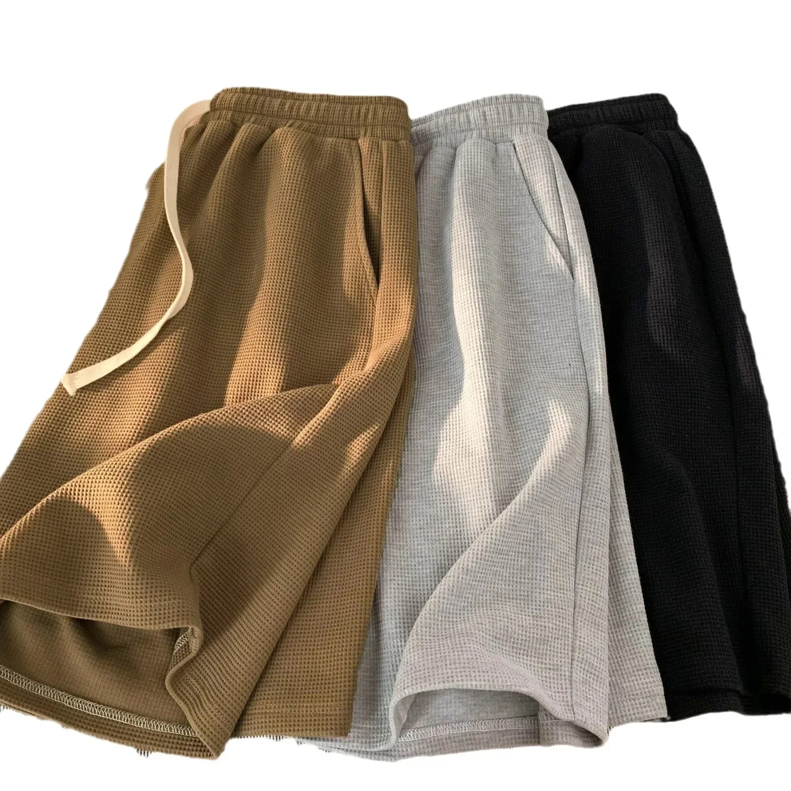 Three pairs of shorts in brown, gray, and black on a white background