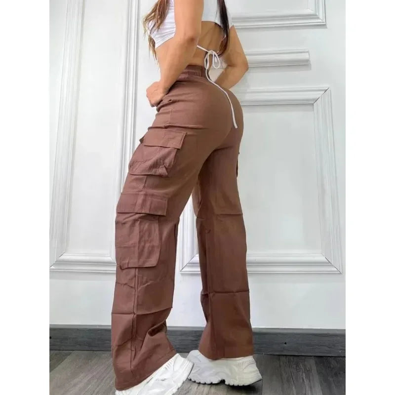 Person wearing brown cargo pants standing against a white wall.
