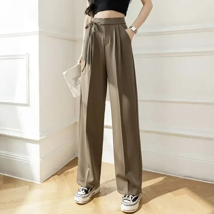 Person wearing beige wide-leg pants in a room with a window.