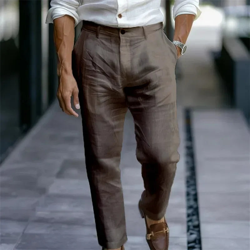 Person wearing brown pants and a white shirt on a blurred street background