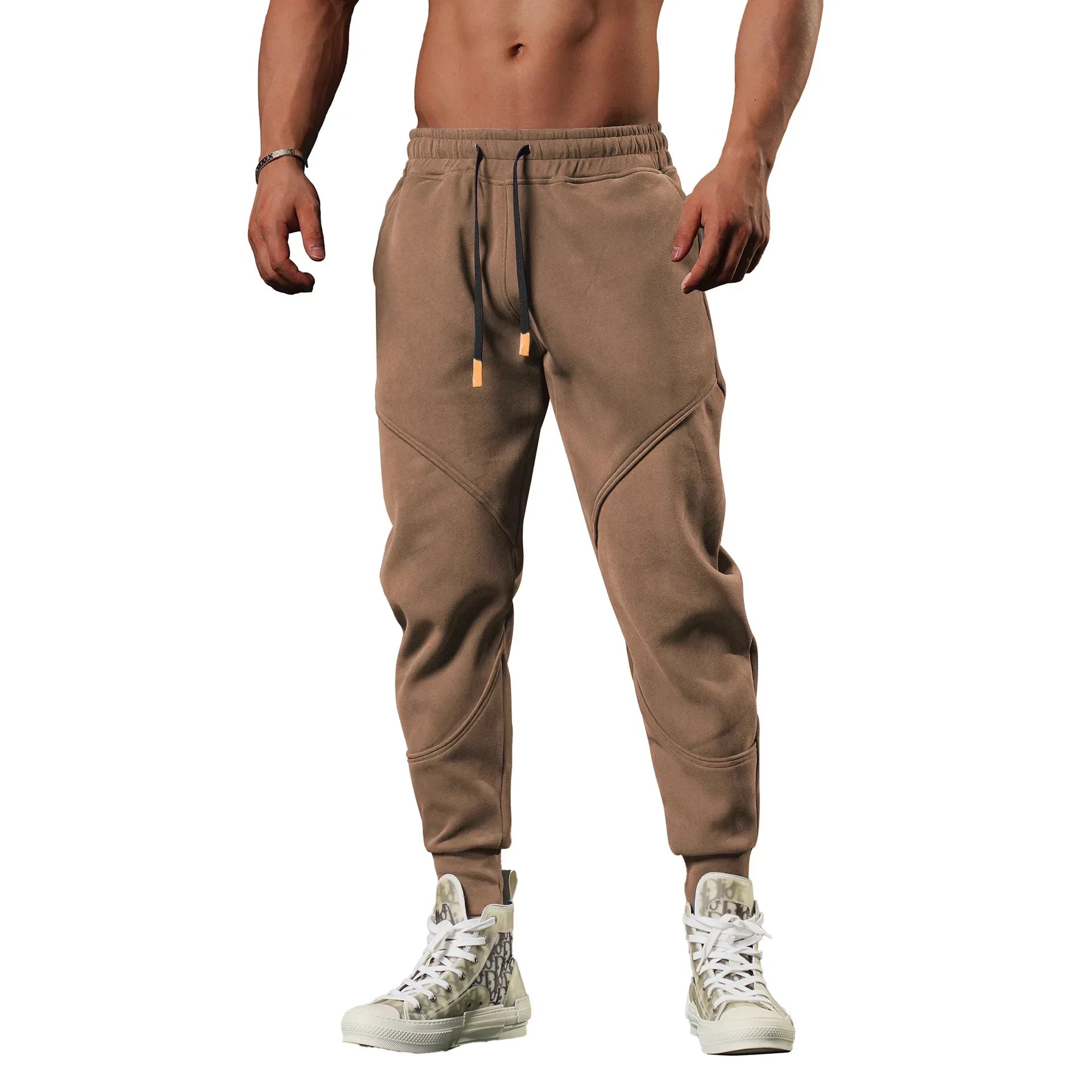 Brown jogger pants worn by a person on a white background