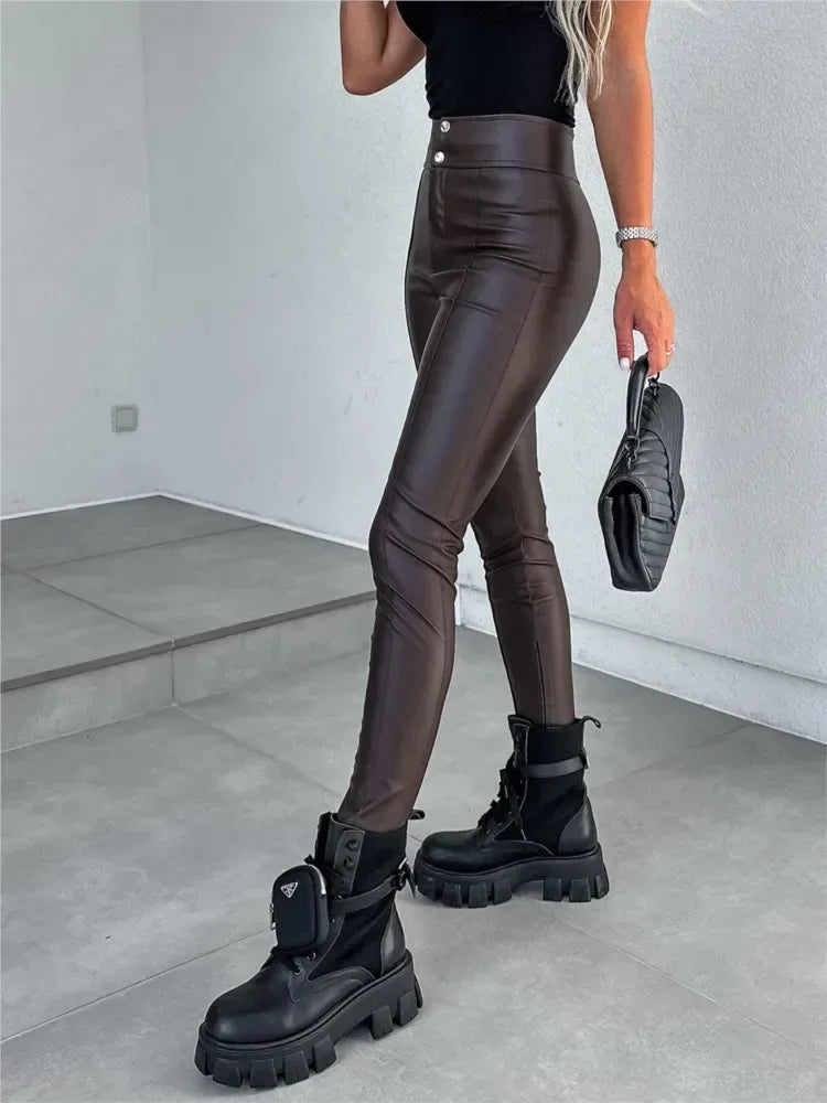Person wearing brown leather pants and black boots in a minimalistic setting