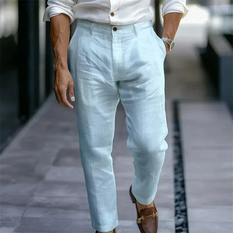 Person wearing light blue pants and a white shirt on a blurred street background